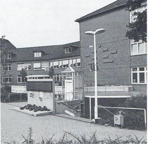 Ulrichs, Timm: Zwischen den Zeilen, ursprünglicher Standort, Gesamtansicht mit Schulgebäude (Willy-Brandt-Schule); Foto: Mülheimer Jahrbuch 1992, S. 95.