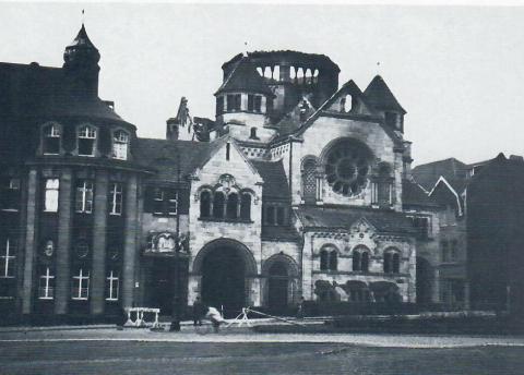 Janssen, Ulfert: Skulpturgruppe über dem Portal der Sparkasse mit ausgebrannter Synagoge (Zustand nach 1938), Foto: Mülheimer Jahrbuch 1984.